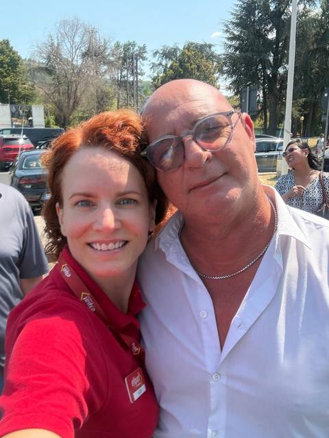 Tour leader and guest smile for a sunny selfie outside a tour coach.