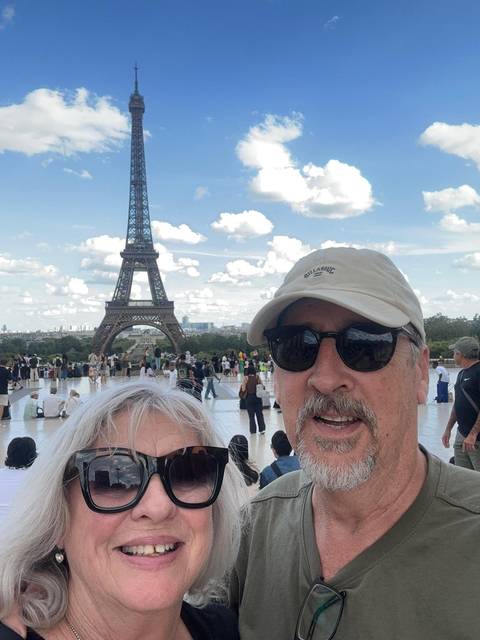 Couple takes a selfie at Trocadéro with the Eiffel Tower towering behind on a sunny afternoon.
