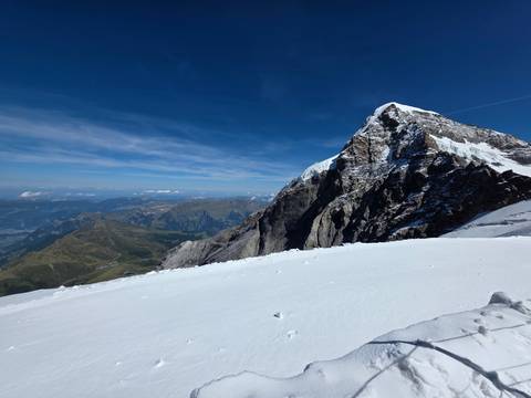 Dramatic snowy mountain ridge and pristine white slope under a deep blue sky.