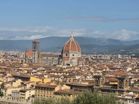 Panoramic view of Florence with the iconic red-tiled Duomo dome rising above the city rooftops.