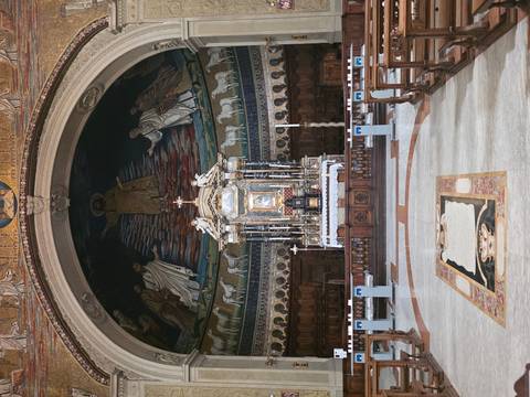 Elegant church apse featuring a mosaic Christ figure above a richly decorated altar.