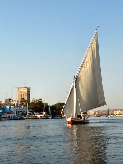 Blurry image of a traditional felucca sailboat on the Nile at sunset.