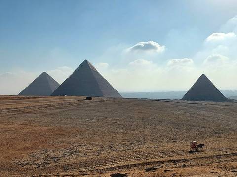 Iconic silhouette of the three pyramids of Giza rising from the desert plateau.