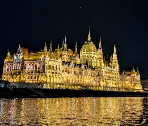 Illuminated neo-Gothic parliament building reflecting on a river at night