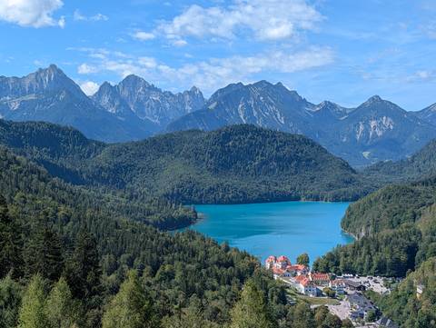 Turquoise alpine lake surrounded by dense forest and rugged mountain peaks