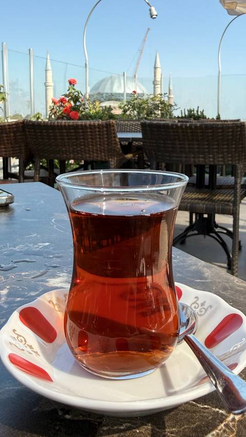 Close-up of a traditional Turkish tea glass filled with dark amber tea on a café table.