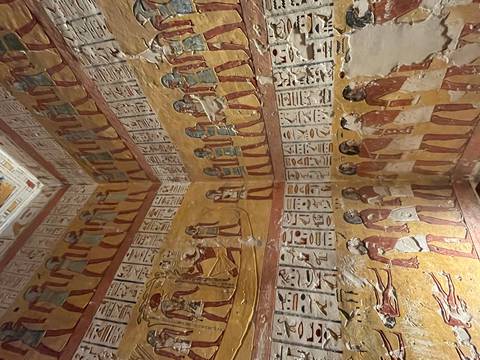 Vivid ancient wall paintings depicting Egyptian figures and hieroglyphs inside a royal tomb chamber.