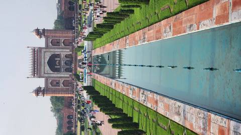 Symmetrical view down the reflecting pool toward the ornate sandstone gateway of the Taj Mahal complex.