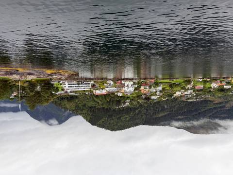 Quaint Norwegian village with colourful houses nestled between forested hills and a calm fjord.