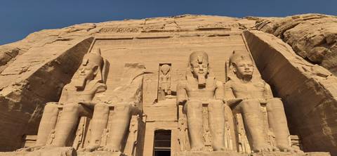 Colossal statues of Ramses II at Abu Simbel temple carved into sandstone cliff