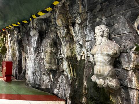 Stockholm metro station decorated with classical stone torso sculptures set into rocky walls.