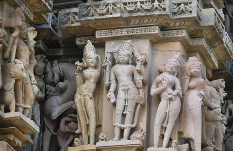 Detailed close-up of intricately carved sandstone figures adorning the façade of an ancient Khajuraho temple.