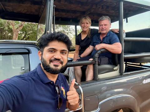 Selfie of a driver and two travellers sitting in an open safari jeep ready for an excursion.