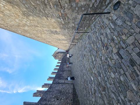 Visitors walk up a cobbled ramp between high stone walls of a Swiss hilltop fortress