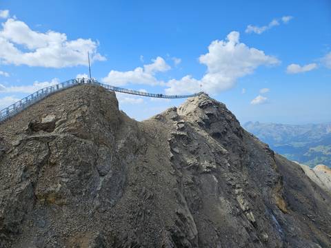 Dramatic suspension footbridge spans two rocky alpine peaks high above the surrounding mountains