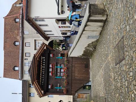 Charming cobbled street and chalet-style restaurant in Gruyères with visitors strolling uphill