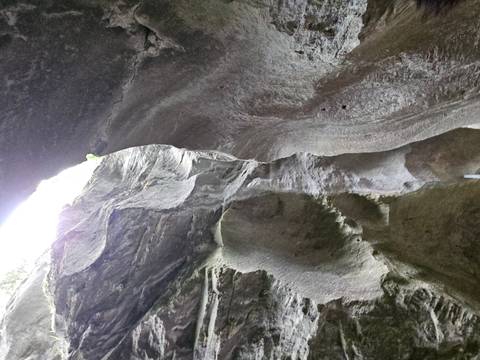 Tall stone walls curve overhead inside a narrow gorge with light streaming from the opening above
