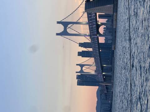 Gwangan Bridge and modern Busan skyline glowing at pastel sunset over calm bay.