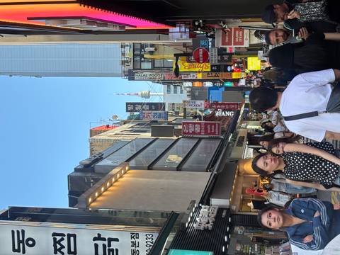 Bustling shopping street lined with signs and shoppers, with N Seoul Tower visible in the distance.
