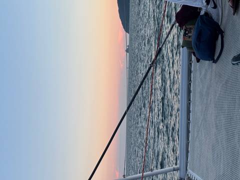 Peaceful sunset from a catamaran deck over calm sea and pastel horizon.