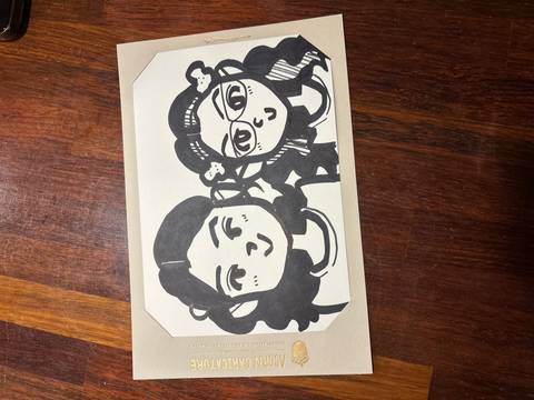 Black-and-white cartoon portrait drawing of two girls on a sheet of paper.