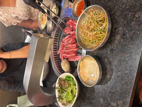 Korean BBQ grill with marbled beef and fresh side dishes ready to cook at the table.