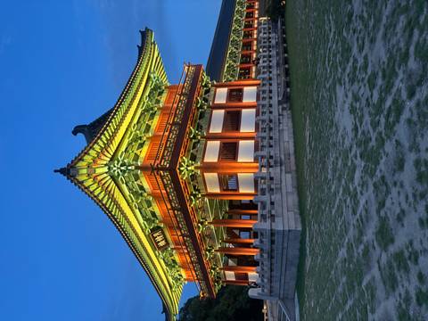 Ornately lit traditional pavilion glows against a deep blue evening sky.