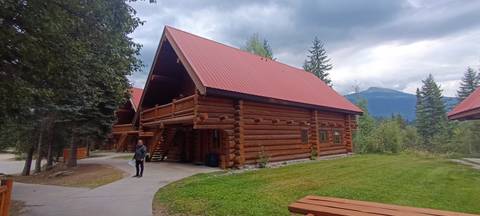 Rustic log cabin lodge with red metal roof set among forested mountains