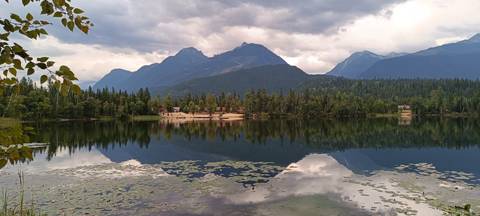 Serene mountain lake with lily pads and dramatic sky reflections