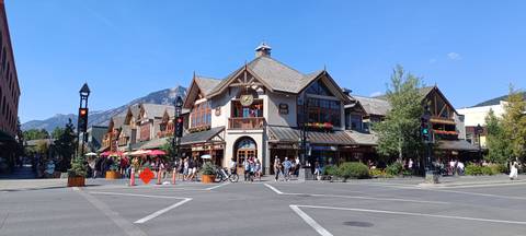 Busy summer street scene in Banff town with Alpine-style architecture and mountain backdrop