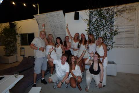 Young travellers dressed in white celebrate together at night in an outdoor venue.