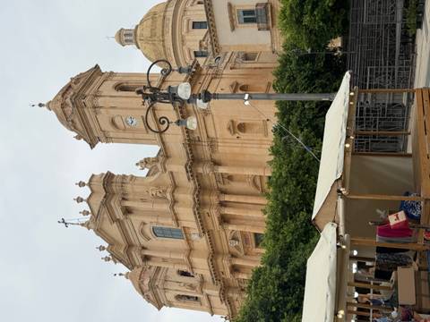 Baroque sandstone cathedral with twin bell towers and ornate façade rises above a small market stall.
