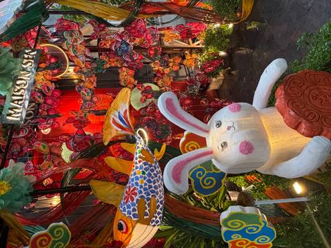 Colourful night display of lanterns, butterflies and a smiling rabbit statue outside Maison Sen.