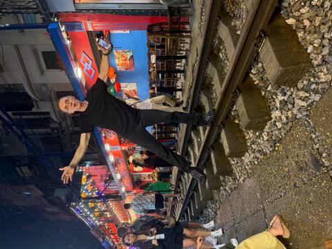 Traveller playfully balancing on the tracks at Hanoi’s famous Train Street lit by colourful lanterns.