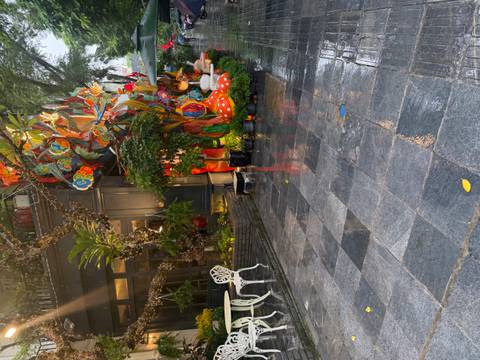 Decorative outdoor corner with colourful mushroom statues and plants reflected on wet pavement after rain.