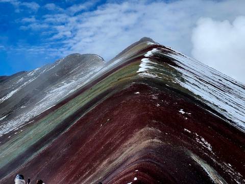 Sharp multicoloured ridge of Rainbow Mountain dusted with snow cuts against the sky.