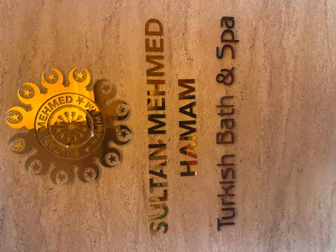 Close-up of a polished wall sign reading 'Sultan Mehmed Hamam Turkish Bath & Spa'.
