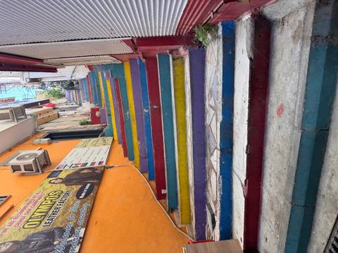 Narrow urban staircase painted in bright rainbow colors ascends between residential buildings.