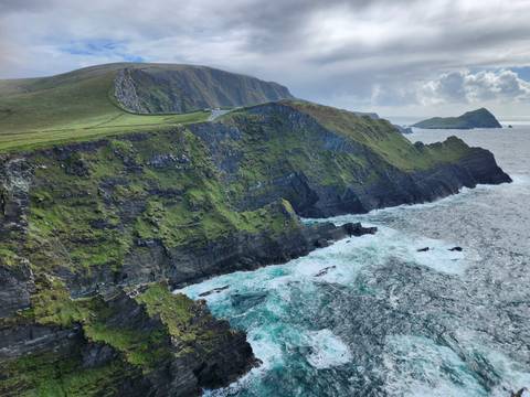 Steep green cliffs meeting turquoise Atlantic waters along the Ring of Kerry coastal road