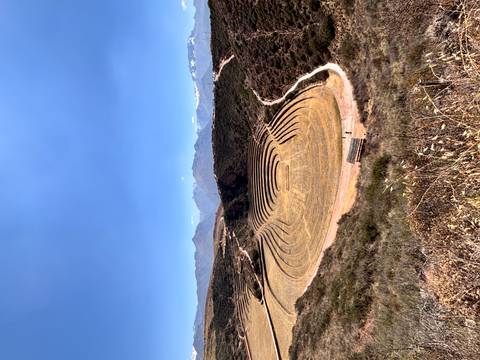 Panoramic view of the circular agricultural terraces of Moray with snow-capped Andes in the distance.