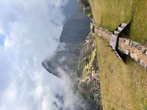 Iconic view of Machu Picchu terraces with mist swirling around steep Huayna Picchu peak.