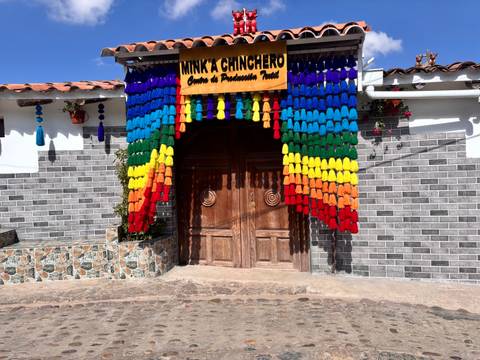 Wooden doorway framed by bright rainbow tassels at Minka Chinchero textile centre.