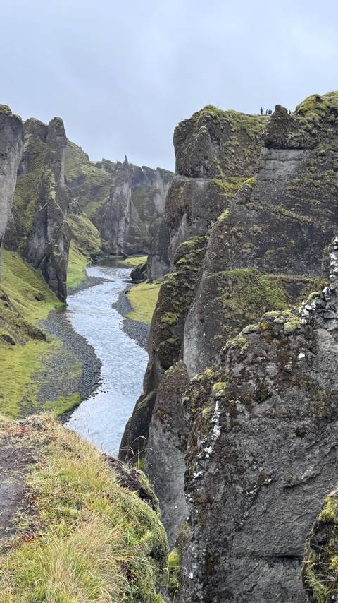 Narrow river winding through steep moss-covered canyon walls at Fjadrargljufur.