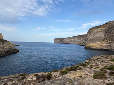 Quiet blue inlet surrounded by tall limestone cliffs on Gozo island
