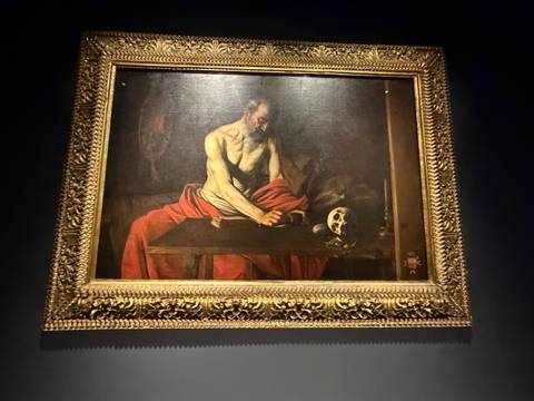 Framed classical painting depicting Saint Jerome displayed in a dimly lit gallery