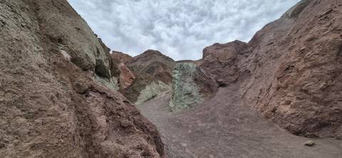 Color-streaked badlands and rugged hills beneath a cloudy sky in Death Valley’s Artist’s Palette.