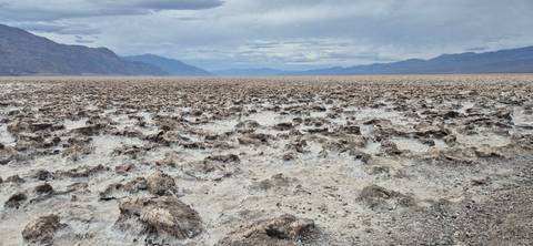 Vast expanse of jagged salt formations known as Devil’s Golf Course stretching to distant mountains.