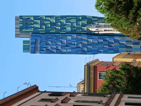 Modern high-rise with mosaic blue façade towering above colourful historic buildings in downtown Tirana.