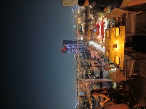 Night rooftop restaurant table overlooking illuminated skyline of Tirana with landmark tower.