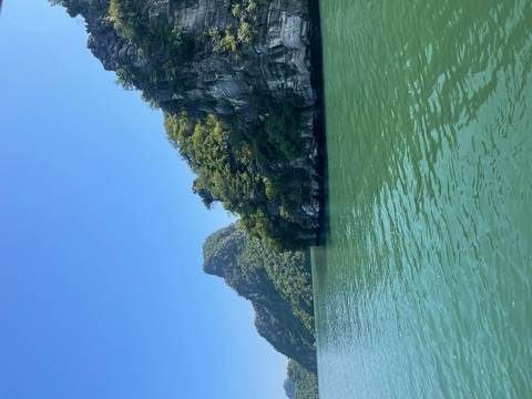 Emerald green waters and limestone karst cliffs of Halong Bay under a clear blue sky.